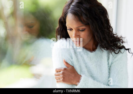 Donna etnica cercando triste sat in una finestra Foto Stock