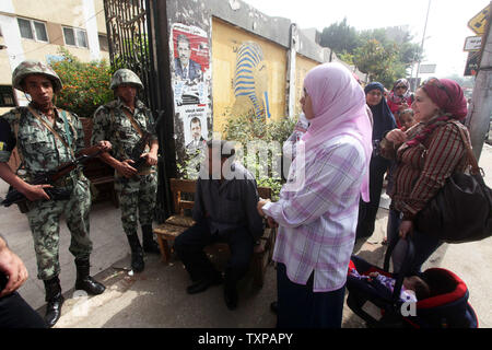 Un egiziano soldati dell esercito sta di guardia all'interno di una stazione di polling come donne di attendere per il loro voto nel paese di elezione presidenziale, al Cairo in Egitto. Il 23 maggio 2012. Gli egiziani sono andati a votare il mercoledì mattina per eleggere un nuovo presidente dopo la caduta dell ex-Presidente Hosni Mubarak lo scorso anno. UPI/Ashraf Mohamad Foto Stock