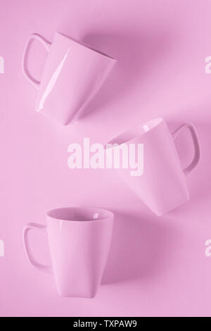 3 rosa monocromatica tazze da caffè sparsi su sfondo rosa con vuoto camera vuoto lo spazio per testo, copiare o copyspace. Moderno vista superiore concetto di thr Foto Stock