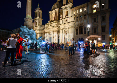 A tarda notte sulla Piazza Navona a Roma Italia come turisti e enti locali italiani godetevi la vivace atmosfera, fontane illuminate e artisti di strada. Foto Stock