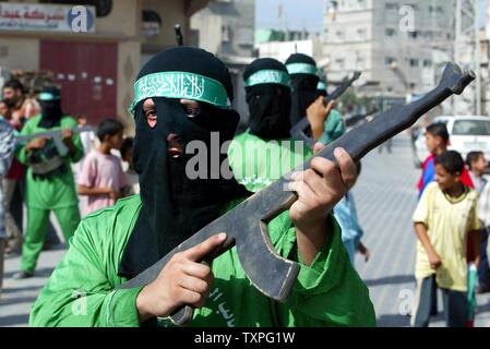 Mascherare i membri di Hamas' ala armata, Ezzedine al-Qassam brigate, tenere premuto fake fucili e fake usura cinghie esplosiva durante un rally in Jabalya Refugee Camp nel sud della striscia di Gaza, il 24 ottobre 2003. Palestinesi gruppi militante Hamas e la Jihad islamica congiuntamente rivendicato oggi la responsabilità per una notte durante un attacco su un insediamento ebraico nella Striscia di Gaza che ha lasciato tre israeliani e uno dei banditi morti. (UPI/Ismael Mohammad) Foto Stock