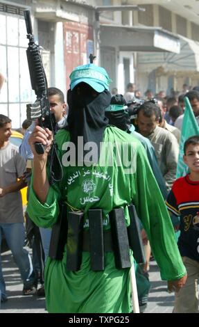 Mascherare i membri di Hamas' ala armata, Ezzedine al-Qassam brigate, tenere premuto fake fucili e fake usura cinghie esplosiva durante un rally in Jabalya Refugee Camp nel sud della striscia di Gaza, il 24 ottobre 2003. Palestinesi gruppi militante Hamas e la Jihad islamica congiuntamente rivendicato oggi la responsabilità per una notte durante un attacco su un insediamento ebraico nella Striscia di Gaza che ha lasciato tre israeliani e uno dei banditi morti. (UPI/Ismael Mohammad) Foto Stock