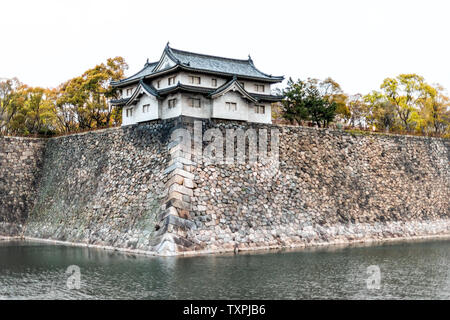 Osaka, Giappone fossato della piscina durante il giorno di primavera con il castello reale e il muro di pietra wiith nessuno su nuvoloso Foto Stock