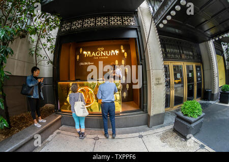 Ice Cream amanti passo fino a una finestra di Saks Fifth Avenue a New York che ha il vetro rimosso e viene rimodellata in un "Ice Cream Parlor" per il buon umore Co. Magnum del mini-bar give-away Martedì, 18 giugno 2019. Magnum, che è una marca di buon umore, che di per sé è di proprietà del conglomerato gigante Unilever, regalato Magnum Mini Bar Gelateria prodotti in vari gusti nel caso di branding. (© Richard B. Levine) Foto Stock