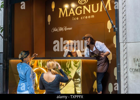 Ice Cream amanti passo fino a una finestra di Saks Fifth Avenue a New York che ha il vetro rimosso e viene rimodellata in un "Ice Cream Parlor" per il buon umore Co. Magnum del mini-bar give-away Martedì, 18 giugno 2019. Magnum, che è una marca di buon umore, che di per sé è di proprietà del conglomerato gigante Unilever, regalato Magnum Mini Bar Gelateria prodotti in vari gusti nel caso di branding. (© Richard B. Levine) Foto Stock