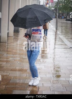 Sheffield, Sud Yorkshrie, UK. Il 25 giugno, 2019. Una donna può contenere fino un ombrello come lei cammina attraverso durante un acquazzone al Moro del mercato del credito: Ioannis Alexopoulos/Alamy Live News Foto Stock