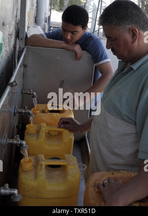 Palestinesi riempire le bottiglie di plastica e taniche con acqua potabile da un pubblico tocca all'Ente soccorso e lavori delle Nazioni Unite UNRWA sede nel sud della striscia di Gaza un campo di rifugiati di Rafah, Aprile 08, 2012. .La striscia di Gaza è in preda ad una grave crisi di potenza per mesi con la sua unica centrale elettrica in grado di funzionare a causa di una interruzione di alimentazione di carburante al territorio. UPI/Ismael Mohamad Foto Stock