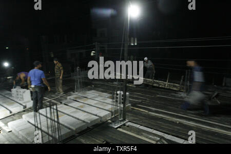 Costruzione palestinese lavoratori lavorare di notte a Rafah nella striscia di Gaza meridionale il 27 luglio 2012. I lavoratori palestinesi il lavoro durante la notte nel mese di Ramadan a causa delle alte temperature diurne. Inoltre i lavoratori non possono lavorare durante il giorno quando sono a digiuno. UPI/Ismael Mohamad Foto Stock