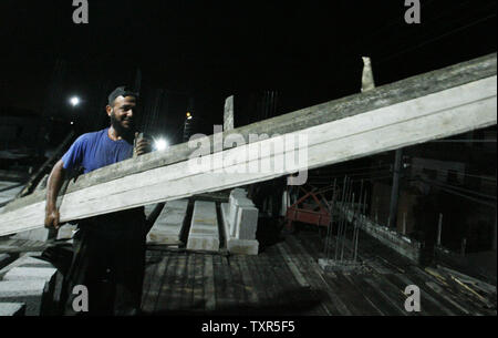 Costruzione palestinese lavoratori lavorare di notte a Rafah nella striscia di Gaza meridionale il 27 luglio 2012. I lavoratori palestinesi il lavoro durante la notte nel mese di Ramadan a causa delle alte temperature diurne. Inoltre i lavoratori non possono lavorare durante il giorno quando sono a digiuno. UPI/Ismael Mohamad Foto Stock