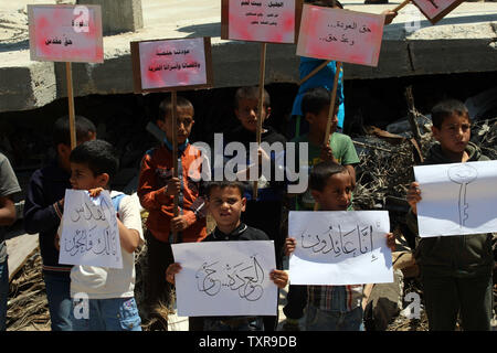 Bambini palestinesi holding cartelloni e poster con le parole arabe "Ci torneremo sicuramente l' durante un rally segnando il sessantasettesimo anniversario della "La Nakba" il 15 maggio 2015. vicino al confine con Israele, a est di Khan Younis nel sud della striscia di Gaza. 'La Nakba" significa in arabo "catastrofe" in riferimento alla nascita dello Stato di Israele 67 anni fa in British-Palestina mandataria, che ha causato lo sfollamento di centinaia di migliaia di palestinesi che sono fuggiti o sono stati cacciati dalle loro case durante la guerra del 1948 su Israele per la creazione. Foto di Ismael Mohamad/UPI Foto Stock