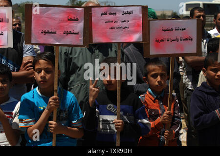 Bambini palestinesi holding cartelloni e poster con le parole arabe "Ci torneremo sicuramente l' durante un rally segnando il sessantasettesimo anniversario della "La Nakba" il 15 maggio 2015. vicino al confine con Israele, a est di Khan Younis nel sud della striscia di Gaza. 'La Nakba" significa in arabo "catastrofe" in riferimento alla nascita dello Stato di Israele 67 anni fa in British-Palestina mandataria, che ha causato lo sfollamento di centinaia di migliaia di palestinesi che sono fuggiti o sono stati cacciati dalle loro case durante la guerra del 1948 su Israele per la creazione. Foto di Ismael Mohamad/UPI Foto Stock