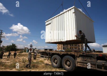 Un confine egiziano appare sullo sfondo come il palestinese Hamas le forze di sicurezza di mettere un nuovo case mobili la zona di frontiera di Rafah tra Gaza ed Egitto su Aprel 14, 2016. Hamas chiede l Egitto per allentare il blocco da Gaza come chiamate in Egitto per Hamas di aumentare il numero di truppe e di controllo della frontiera tra Egitto e la striscia di Gaza .Hamas chiamato per l'Egitto per allentare le restrizioni sulla striscia di Gaza, un delegato detto, dopo da funzionari del gruppo islamista recato al Cairo per cercare di ricucire rapporti tesi. Alto funzionario Khalil al-Haya detto Hamas aveva implorato Egitto per consentire più il traffico attraverso il Foto Stock