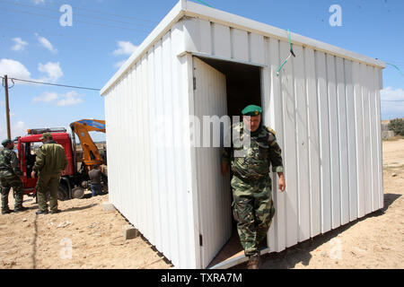 Un confine egiziano appare sullo sfondo come il palestinese Hamas le forze di sicurezza di mettere un nuovo case mobili la zona di frontiera di Rafah tra Gaza ed Egitto su Aprel 14, 2016. Hamas chiede l Egitto per allentare il blocco da Gaza come chiamate in Egitto per Hamas di aumentare il numero di truppe e di controllo della frontiera tra Egitto e la striscia di Gaza .Hamas chiamato per l'Egitto per allentare le restrizioni sulla striscia di Gaza, un delegato detto, dopo da funzionari del gruppo islamista recato al Cairo per cercare di ricucire rapporti tesi. Alto funzionario Khalil al-Haya detto Hamas aveva implorato Egitto per consentire più il traffico attraverso il Foto Stock