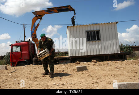 Un confine egiziano appare sullo sfondo come il palestinese Hamas le forze di sicurezza di mettere un nuovo case mobili la zona di frontiera di Rafah tra Gaza ed Egitto su Aprl 14, 2016. Hamas chiede l Egitto per allentare il blocco da Gaza come chiamate in Egitto per Hamas di aumentare il numero di truppe e di controllo della frontiera tra Egitto e la striscia di Gaza .Hamas chiamato per l'Egitto per allentare le restrizioni sulla striscia di Gaza, un delegato detto, dopo da funzionari del gruppo islamista recato al Cairo per cercare di ricucire rapporti tesi. Alto funzionario Khalil al-Haya detto Hamas aveva implorato Egitto per consentire più il traffico attraverso il Foto Stock