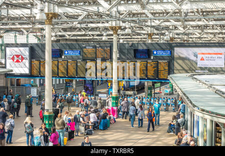 Scena in interni di un occupato la stazione ferroviaria Waverley di Edimburgo, con la luce del sole lo streaming attraverso il vetro e il tetto di travi. La Scozia, Regno Unito. Foto Stock