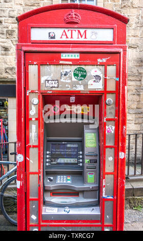 Un dismesse, iconico ma sporca, British telefono rosso scatola, intelligentemente convertito a un bancomat, sul Royal Mile di Edimburgo, Scozia, Regno Unito. Foto Stock