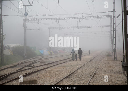 Una famiglia è raffigurato a camminare tra la nebbia avvolta i binari della ferrovia dove un migrante il camp è stato istituito per loro e per le altre persone che si trovano in situazioni analoghe. Le madri e i bambini e le famiglie sono tra i 12.000 rifugiati che approdano in un campo di fortuna in Idomeni, Grecia, lungo il confine con la Macedonia in aprile 2016 dopo il confine era chiuso. Foto di David Caprara/UPI Foto Stock