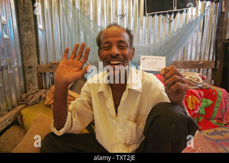 Mohamed Ismail, padre dei musulmani indiani e 'Slumdog milionario' attore bambino Mohammed Azharuddin Ismail (non visibile) sorrisi come egli era in possesso di un biglietto da visita in una delle baraccopoli in Oriente Bandra di Mumbai, in India il 16 marzo 2009. (UPI foto/Mohammad Kheirkhah) Foto Stock