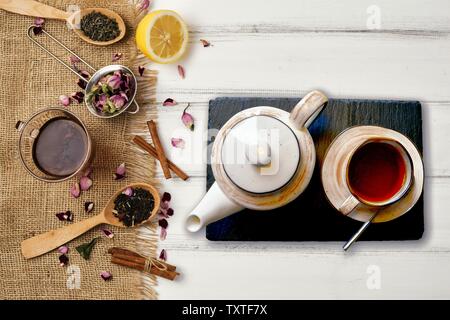 Colpo di testa di una tazza di tè piena di nero tè e tè bianco con spezie e prodotti di cortesia Foto Stock