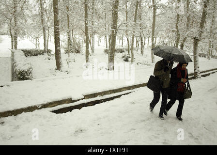 Un giovane iraniana scudi stessi con un ombrello mentre la neve cade nel Parco Laleh di Teheran, Iran il 6 gennaio 2008. La neve ricopriva Teheran e molte altre città in tutto il paese che conduce alla chiusura delle scuole e persino in alcune università sia nella capitale e in altre città. Molte strade che conducono a Teheran e la maggior parte delle strade di tutto il paese e in particolare nel nord, nord-ovest e le parti occidentali, sono state bloccate a causa delle pesanti nevicate e bufere di neve. Lo stato compagnie di aviazione (HOMA) annullato tutti i voli nazionali fino a metà giornata di domenica, IRNA segnalati. (UPI foto/Mohammad Foto Stock