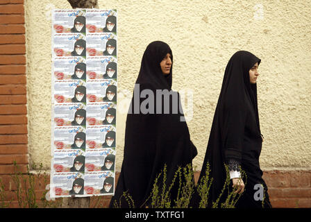 Due donne iraniane passare dietro i manifesti di Fatemeh Karrubi, uno dei candidati per la prossima 8 elezioni parlamentari in Tehran, Iran il 10 marzo 2008. Dell'Iran elezioni del Parlamento europeo si terrà il 14 marzo. (UPI foto/Mohammad Kheirkhah) Foto Stock