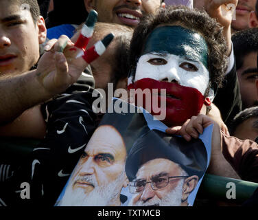 Un iraniano che dipinge il viso con la bandiera iraniana e mantiene un'immagine dell'Iran sulla attuale leader Ayatollah Khamenei(R) e l'Iran del compianto leader Ayatollah Khomeini (L) a Piazza Azadi (Piazza della Libertà) durante la celebrazione del trentaquattresimo anniversario della rivoluzione islamica in Tehran, Iran il 10 febbraio 2013. UPI/Maryam Rahmanian Foto Stock