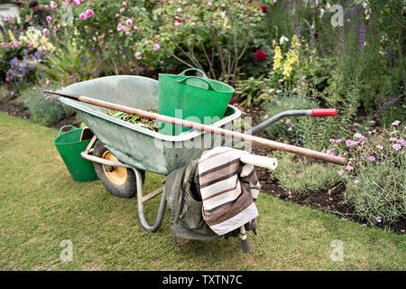 Il National Trust del giardiniere carriola con strumenti e trugs sul prato a Mottisfont Foto Stock