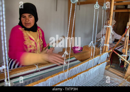 Khizana, Chefchaouen, Marocco - 2 Maggio 2019: una donna di filatura in un antico telaio della cooperativa femminile nella zona rurale di Khizana, Chefchaouen, Moroc Foto Stock