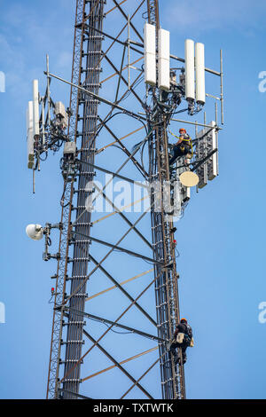 Il Cantone, Ohio lake, STATI UNITI D'AMERICA. Maggio 8, 2019. Manutenzione di comunicazione. Due tecnici arrampicata su telecom antenna torre contro il cielo blu sullo sfondo Foto Stock