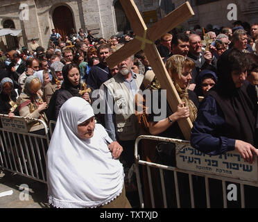 Un palestinese musulmana passeggiate passato pellegrini cristiani croci sulla Via Dolorosa, il tradizionale percorso dove Gesù ha portato la sua croce, durante la processione del Venerdì santo nella Città Vecchia di Gerusalemme, Aprile 9, 2004. (UPI foto/Debbie Hill) Foto Stock