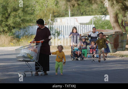 Un colono israeliano ritorna dal supermercato con bambini nell'insediamento ebraico di Netzarim nella Striscia di Gaza, 13 aprile 2004. Il primo ministro Israeliano Ariel Sharon è in America per discutere il suo unilaterale del piano di ritiro dalla Striscia di Gaza con il Presidente USA George Bush a Washington D.C. il mercoledì. Il primo ministro palestinese Ahmed Qureia detto che Sharon del piano di trattenere 5 grandi West Bank Settlement blocs distrugge ogni possibilità per la pace. (UPI foto/Debbie Hill) Foto Stock