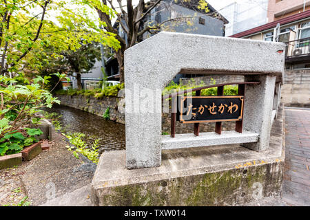 Kyoto quartiere residenziale in primavera con il segno nella traduzione giapponese per il fiume Takase canal acqua in aprile in Giappone con alberi verdi piante Foto Stock