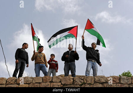 Gioventù palestinese bandiere d'onda durante una manifestazione di protesta contro la chiusura di Shuhada Street ai palestinesi a Hebron, West Bank, 25 febbraio 2011. Manifestanti hanno gridato slogan contro gli Stati Uniti per vetoing la risoluzione del Consiglio di Sicurezza delle Nazioni Unite che condanna gli insediamenti israeliani. UPI/Debbie Hill. Foto Stock