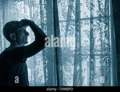 Uomo maturo con la mano sulla testa vicino alla finestra. Concetto di immagine per la depressione, depressione maschio, salute mentale, maschio suicida... Foto Stock