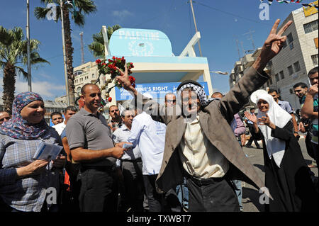 Un palestinese di balli e dà il segno di vittoria davanti a un grande valore simbolico delle Nazioni Unite nella sede centrale di Ramallah, West Bank, dopo una cerimonia di inaugurazione, 20 settembre 2011. Il presidente palestinese Mahmoud Abbas affronterà le Nazioni Unite Venerdì, Settembre 23, 2011, in un'offerta per la Palestina per raggiungere lo status di membro a pieno titolo membro dell'ONU. UPI/Debbie Hill Foto Stock