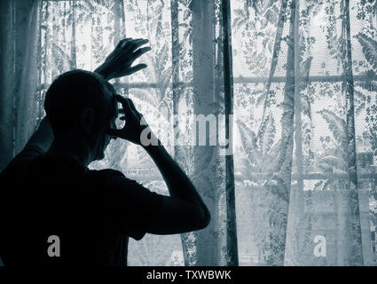 Uomo maturo con la mano sulla testa vicino alla finestra. Concetto di immagine per la depressione, depressione maschio, salute mentale, maschio suicida... Foto Stock
