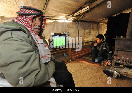 Palestinesi guardare una partita di calcio su un televisore alimentato da pannelli solari in Umm Al Kheir comunità beduina nel sud delle colline di Hebron, West Bank, febbraio 29, 2012. Il popolo israeliano di amministrazione civile ha emesso ordini di demolizione per le energie rinnovabili impianti a pannelli solari e turbine a vento che forniscono elettricità ai palestinesi che Israele si rifiuta di gancio fino alla rete elettrica. Le installazioni di energia sono stati pagati dal Ministero tedesco degli Affari Esteri e avviato da volontari israeliani. L'energia elettrica prodotta da pannelli solari e turbine eoliche ha rivoluzionato Foto Stock