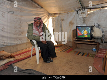 Un palestinese orologi di una partita di calcio su un televisore alimentato da pannelli solari in Umm Al Kheir comunità beduina nel sud delle colline di Hebron, West Bank, febbraio 29, 2012. Il popolo israeliano di amministrazione civile ha emesso ordini di demolizione per le energie rinnovabili impianti a pannelli solari e turbine a vento che forniscono elettricità ai palestinesi che Israele si rifiuta di gancio fino alla rete elettrica. Le installazioni di energia sono stati pagati dal Ministero tedesco degli Affari Esteri e avviato da volontari israeliani. L'energia elettrica prodotta da pannelli solari e turbine eoliche ha revolutioni Foto Stock