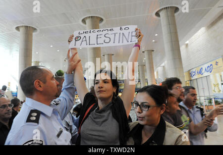 Un israeliano undercover poliziotta (R) arresti una sinistra militante tenendo un pro-palestinese slogan all'aeroporto Ben Gurion vicino a Tel Aviv il 15 aprile 2012. Centinaia di polizia israeliana, molti undercover, sono state distribuite in aeroporto per bloccare l'arrivo di pro-attivisti palestinesi prendendo parte ad un 'Benvenuti alla Palestina' fly-in. Israele fece per impedire l'ingresso di attivisti, avvertimento le compagnie aeree straniere sarebbero costretti a pagare il conto per gli attivisti' immediato ritorno a casa. UPI/Debbie Hill Foto Stock