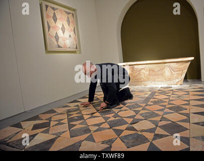 Un lavoratore si prepara un pavimento a mosaico in prossimità di una vasca da bagno in pietra scavato dal bagno caldo casa del re Erode palace a Cypros, parte di una mostra intitolata "Erode il Grande: Del Re ultimo viaggio,' nel Museo di Israele, a Gerusalemme, Israele, 12 febbraio 2013. La mostra si occupa di 40 anni di scavi archeologici della vita e l'eredità del re Erode che è ricordato come il più grande costruttore nella storia umana. Egli è conosciuto per elaborare i palazzi, fortezze, come Masada, e la ricostruzione del tempio di Gerusalemme in epoca romana. Erode governata per oltre trenta anni in che cosa ora è k Foto Stock