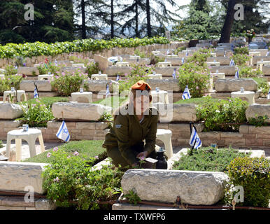 Un soldato israeliano decora le tombe dei soldati caduti con bandiere nazionali con nastri di nero per il giorno del ricordo presso il Mt. Herzl Cimitero militare di Gerusalemme, Israele, 14 aprile 2013. Israele il giorno del ricordo per i caduti inizia al tramonto con un minuto di sirena. UPI/Debbie Hill Foto Stock