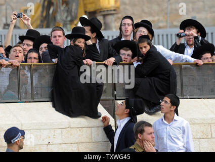 Ultra-Orthodox uomini guardano la progressiva organizzazione ebraica le donne della parete, non visto, pregare indossando il tradizionale articoli religiosi utilizzato solo da uomini, presso il Muro Occidentale, giudaismo del sito più sacro, a Gerusalemme, Israele, Giugno 9, 2013. Più di 300 donne pregavano dietro una barriera al Muro Occidentale come polizia di frontiera impedito Ultra-Orthodox uomini dal raggiungimento di esse mentre indossava tefillin e scialli di preghiera per celebrare il primo giorno del mese ebraico di Tamuz. Le donne della parete hanno lottato per la libertà religiosa e i diritti delle donne presso il Muro Occidentale per più di venticinque anni. UPI/Debbie Hill Foto Stock