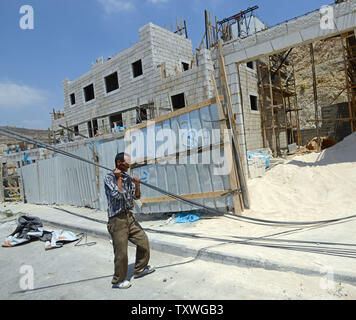 Un palestinese opere sul nuovo alloggiamento israeliano di unità nell'insediamento ebraico di Givat Ze'ev, West Bank, luglio 17, 2013. Il popolo israeliano di amministrazione civile si aspettano di approvare 900 unità abitative nei vari Cisgiordania insediamenti. L'Unità Europea ha annunciato nuove linee guida per il sostegno finanziario a Israele. Le nuove regole bar tutti cooperazione con enti israeliani in Cisgiordania, Gerusalemme est e Alture del Golan, che include tutti i finanziamenti, la cooperazione e la concessione di borse di studio, assegni di ricerca e i prezzi. Una clausola della direttiva UE anche membri che Gerusalemme Est e la West Bank e il Golan H Foto Stock