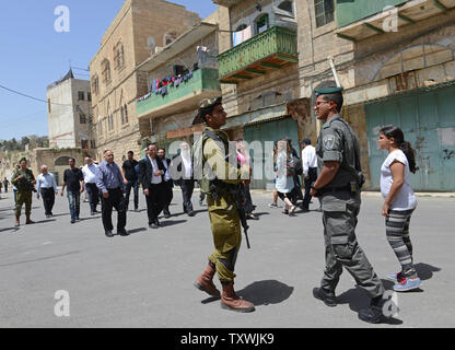 Soldati israeliani israeliani di guardia a piedi passato frantumato negozi palestinese a Hebron, West Bank, 16 aprile 2014, durante la festa di Pasqua. Migliaia di Israeliani e turisti hanno visitato il contestato città di Hebron per pregare accanto alle tombe di Abramo, di Isacco e Rebecca, Lia e Giacobbe e visitare gli insediamenti israeliani. UPI/Debbie Hill Foto Stock