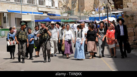 Frontiera israeliana Guardia di polizia un gruppo di turisti israeliani a piedi vicino alla caverna di Macpela, o Grotta dei patriarchi a Hebron, West Bank, 16 aprile 2014, durante la festa di Pasqua. La caverna di Macpela è il luogo di sepoltura che Abrahamo aveva comprato per la sua famiglia ed è il luogo del riposo finale dei patriarchi e matriarche, tranne Rachel morto vicino a Betlemme. Migliaia di Israeliani e turisti hanno visitato il contestato città di Hebron per pregare accanto alle tombe di Abramo, di Isacco e Rebecca, Lia e Giacobbe e visitare gli insediamenti israeliani. UPI/Debbie Hill Foto Stock