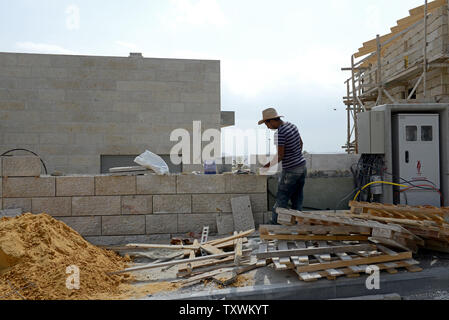 Un lavoratore palestinese costruisce un muro di fronte a una nuova casa degli ebrei nel Ma'ale Adumim insediamento nella West Bank, Settembre 28, 2014. Il presidente palestinese Mahmoud Abbas ha accusato Israele di provocare la pace americana iniziativa di fallire continuando la costruzione di insediamenti durante i negoziati nel suo discorso all'ONU Assemblea generale il venerdì. UPI/Debbie Hill Foto Stock