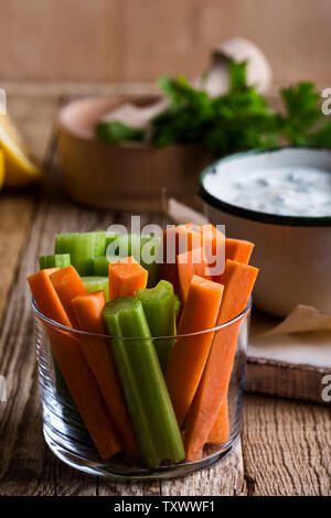 Ortaggi freschi Carote, sedano, yogurt dip con il prezzemolo e il succo di limone servita su tavola in legno rustico con tortilla chips, vegetariano sano Foto Stock