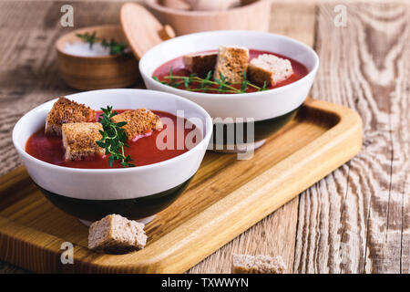 Tradizionale zuppa di pomodoro guarnita con pane di segale crostini e timo, impianto basato cibo, vicino il fuoco selettivo Foto Stock