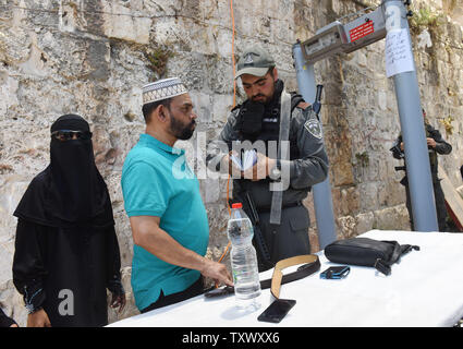 Un israeliano della polizia di frontiera controlla i documenti di palestinesi musulmani a appena installato il rilevatore di metallo in corrispondenza di un ingresso principale al Monte del Tempio, chiamato anche santuario nobile da musulmani, nei pressi della Porta del Leone in Gerusalemme la città vecchia, 16 luglio 2017. La sicurezza di Israele ha riaperto il Monte del Tempio dopo l'installazione di misure di sicurezza aggiuntive, inclusi i rivelatori di metallo e macchine fotografiche, dopo che la Santa Sede è stata chiusa in quanto tre arabi israeliani uccisi due israeliani gli ufficiali di polizia in un attacco di scatto il venerdì. I capi del Jerusalem Islamic Waqf ha rifiutato di inserire il santo sito attraverso il popolo israeliano i rivelatori di metallo Foto Stock