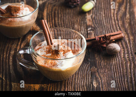 Pumpkin spice latte conditi con panna montata e torta di zucca spezie sulla sommità in tazza di vetro Foto Stock